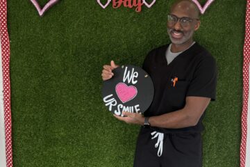 male staff holding ur smile dental board